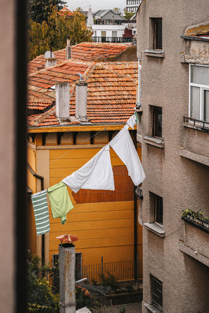 Clean hanging laundry between old buildings under cloudy sky in cozy old urban neighborhood. Concept of daily routine, slow living and authentic lifestyleの写真素材