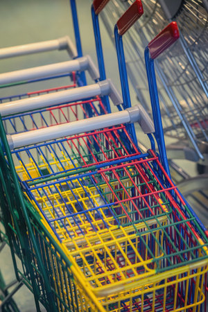 Colorful metal shopping carts in supermarket parking zone. Concept of consumerism, retail industry, modern commerce, vibrant color pattern in everyday urban lifeの写真素材