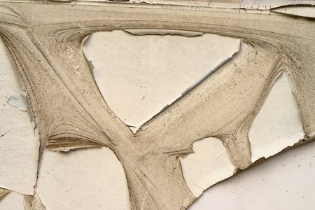 Close-up of cracked peeling paint on aged surface with visible dust and texture details. Concept of...