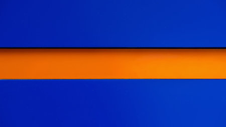 Minimalistic background with bold contrast of deep blue and vivid orange horizontal stripe, copy space. Concept of color contrast, modern design aestheticsの写真素材