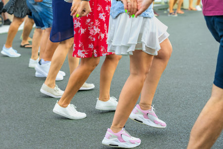 People dancing traditional Bulgarian horo on street, moving rhythmically in line with lively steps, bright summer clothes. Concept of horo dance, tradition, culture, community celebration, folk danceの写真素材