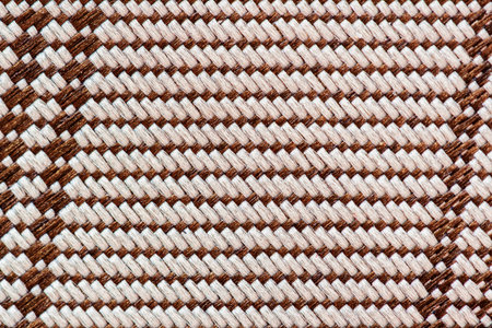 Close-up of traditional woven texture in brown and beige tones with geometric pattern. Natural...