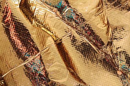 Gold foil abstract texture. Crinkled shiny gold foil surface with abstract reflections and light...