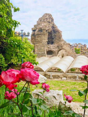 Old Nessebar stone church ruins with tower and arches above garden roses in coastal Bulgaria under...