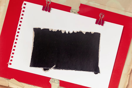 Torn paper rectangle on white notebook page over red folder with binder clips, copy space for note, poster, layout mockup. Natural background of torn paper for message, collage design