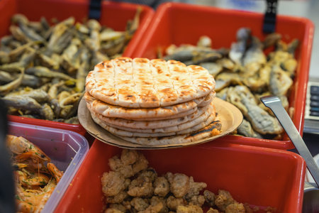 Stack of Grilled Flatbread at Seafood Market Food Stall. Freshly grilled flatbread displayed beside assorted seafood at market food stall. Rustic street food