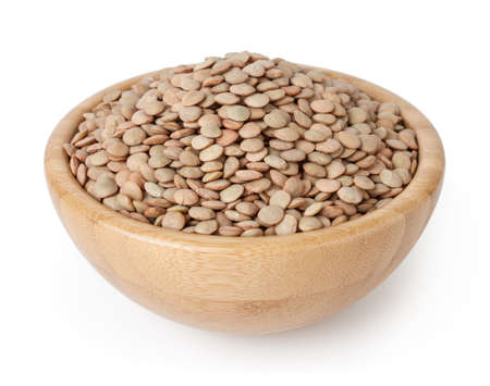 Uncooked lentils in wooden bowl isolated on white background with clipping pathの写真素材