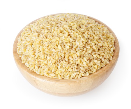 Uncooked bulgur in wooden bowl isolated on white background with clipping pathの写真素材