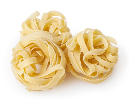 Uncooked nests of tagliatelle pasta isolated on white backgroundの写真素材