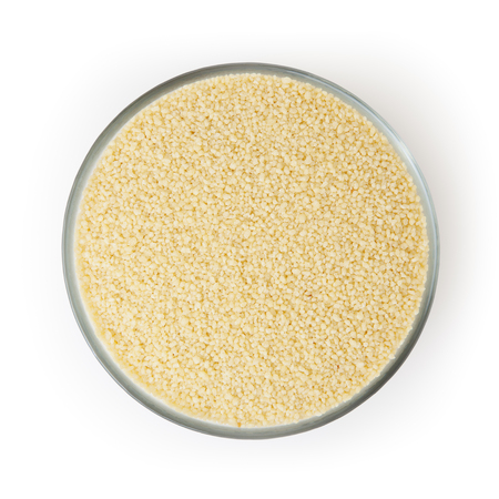 Uncooked couscous in glass bowl isolated on white backgroundの写真素材