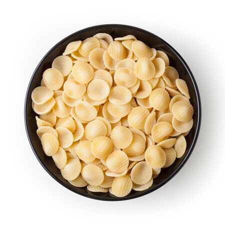 Uncooked orecchiette pasta in black bowl isolated on white backgroundの写真素材