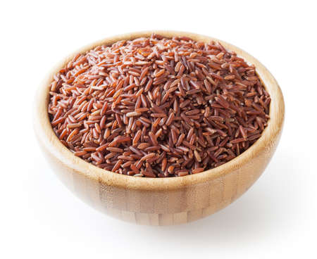 Uncooked red rice in wooden bowl isolated on white backgroundの写真素材