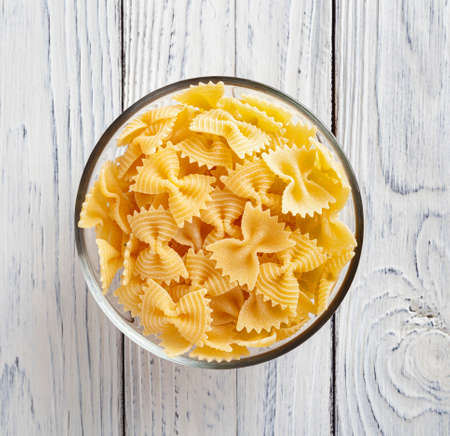 Uncooked farfalle rigate pasta on white wooden backgroundの写真素材