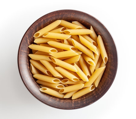 Uncooked penne pasta in ceramic bowl isolated on white backgroundの写真素材