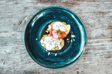 Avocado toast with scrambled eggs on the blue plate on the wood table. Healthy food for breakfastの写真素材