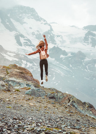 Jumping woman with backpack on mountain background. Top of Gornergrat, Zermatt, Swiss. Alps hikingの写真素材