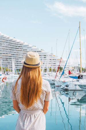 Blonde hair woman in a hat standing with her back on sea, yachts and boats background. Nice, Franceの写真素材