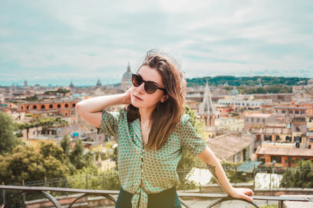 Young brown hair woman in sunglasses with a panoramic view of Rome. Girl traveler on vacation in Italy. Sunny day in southern Europe.の写真素材