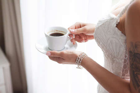 Morning of the bride. Bride drinking coffee at a wedding day. Romantic breakfast. Bride with tattoo...