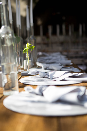 White candles in bottles of wine stand on white table.の写真素材