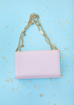 Pink bag on a gold chain. Golden sequins. Blue background.の写真素材