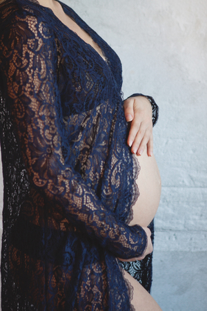 Pregnant woman in blue peignoir hugging her belly.の写真素材