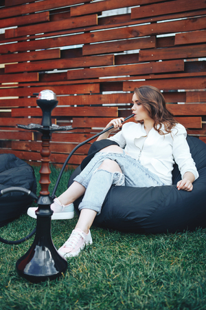 Young woman smoking a hookah outdoors.