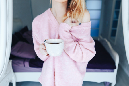 Female hands hold a cup of coffee in the bedroom. Close-up.の写真素材