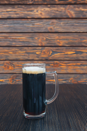 Close-up of a glass of dark beer on a wooden table. wooden background.の写真素材