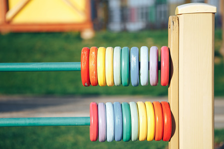 Colour wooden abacus. Colorful wooden circles on the playground. Rings for the development of fine...