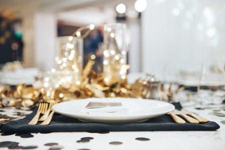 Dinner tableis decorated in black and gold. Garland in a glass flask. Wedding decorationsの写真素材