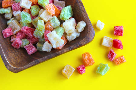 Multicolored candied fruits on a wooden dish on a yellow background, top view.の写真素材