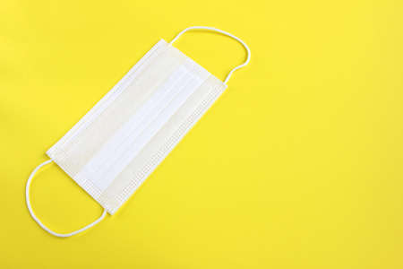White medical protective mask isolated on yellow background.の写真素材