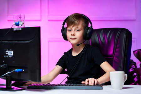 Boy in headphones online streams a computer game live, communicates with his subscribers through a...