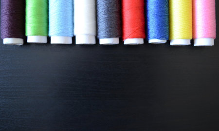 sewing threads on a dark wood background, spools of thread, multicolored threads, sewing accessories, top viewの写真素材