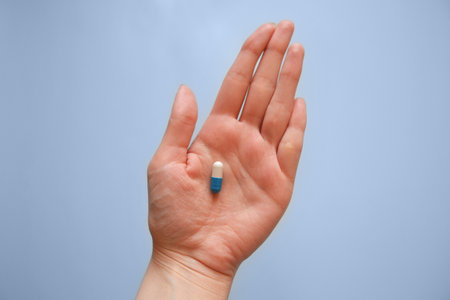 capsule on the palm of your hand on a blue background, medication, day of a medical worker, medical careの写真素材