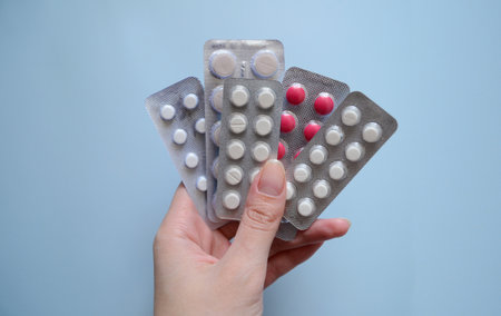 background for a medical website or article, packs of pills in hand on a blue background, medicines, medical careの写真素材