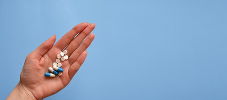 tablets and capsules on the palm of your hand on a blue background, a banner for a medical website, a photo for a medical clinic, a day of a medical workerの写真素材