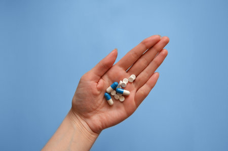 tablets and capsules on the palm of your hand on a blue background, photo for a medical clinic, banner for a medical website, day of a medical workerの写真素材