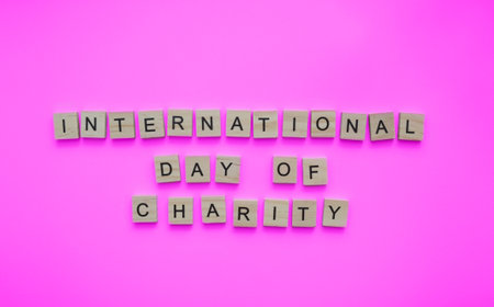 September 5, International Day of Charity, minimalistic banner with the inscription in wooden letters on a pink backgroundの写真素材