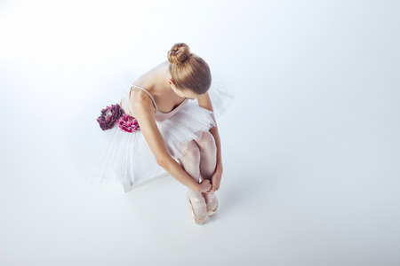 ballerina on a light background sitting on a white cubeの写真素材