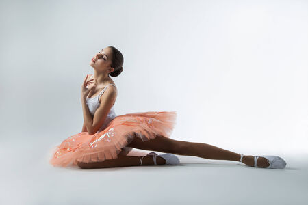 ballerina in a tutu is sitting on the floorの写真素材