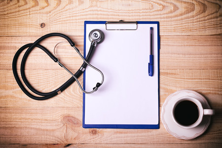 cup of coffee with a stethoscope and notepad to write on a wooden table.の写真素材