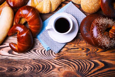 cup of coffee and a bun on the wooden tableの写真素材