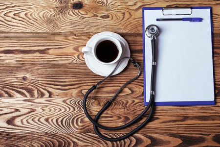 cup of coffee with a stethoscope and notepad to write on a wooden table.の写真素材