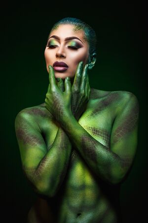 a beautiful young girl and painted body art in the style of the serpentの写真素材