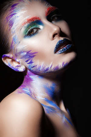 a large portrait of a woman's face on a black background with bright makeup