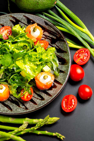 a plate of delicious and healthy salad with red fish, fresh vegetables around the plateの写真素材