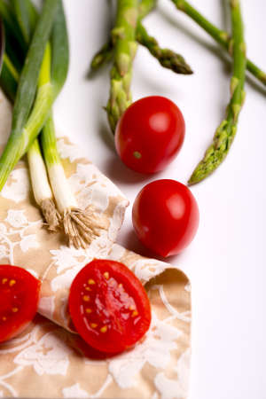 small tomatoes, green asparagus on a white table, ingredients for vegan foodの写真素材
