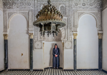 Fes, Morocco - May 11, 2013: Man in berber clothing in an alcove in the inner courtyard of the 14th century  El Attarine Medersa in Fez, Moroccoのeditorial素材
